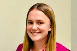 Person mit langen, glatten, blonden Haaren, lächelt, trägt pinke Kleidung.